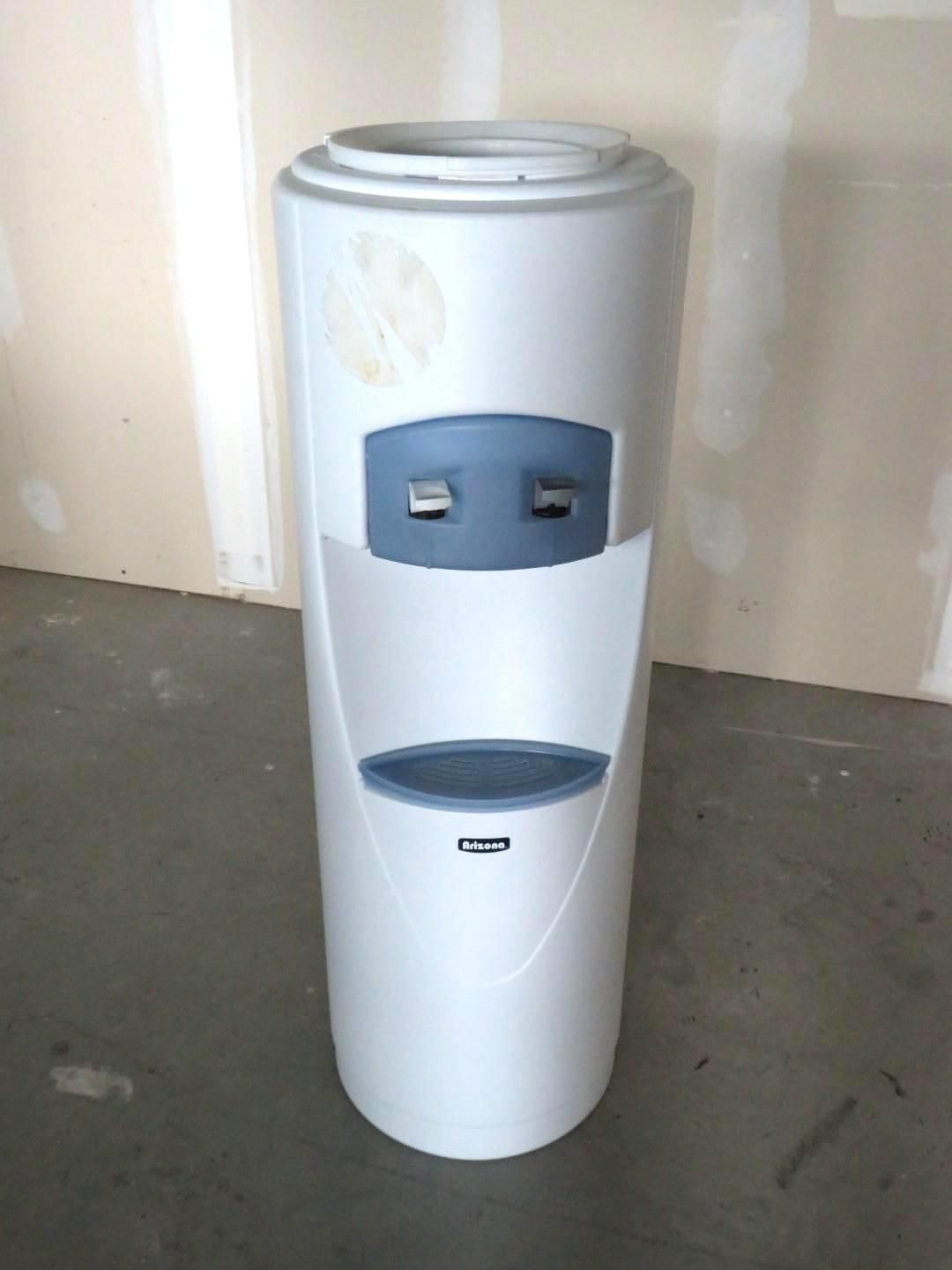 White and gray water cooler with a blue dispensing area, standing on a concrete floor.
