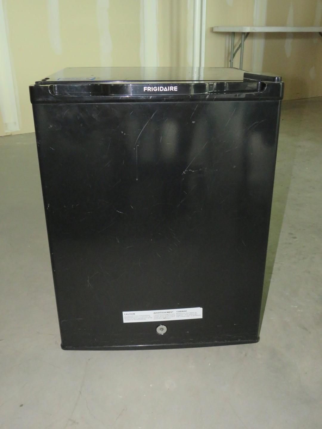 Black Frigidaire chest freezer in a room, on a concrete floor.