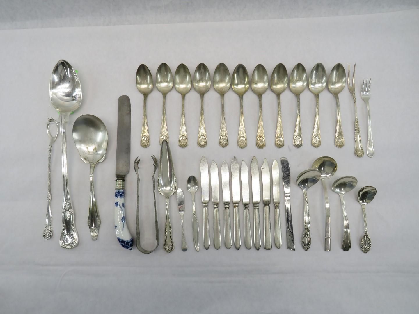 Silverware set: spoons, forks, knives, and serving utensils arranged on a white surface.