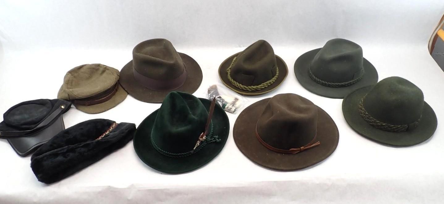 Several hats in black, brown, and green arranged on a white surface