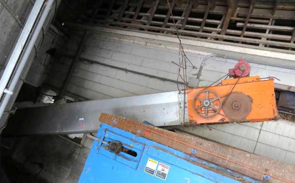 Overhead view of industrial machinery with a conveyor belt, orange and blue parts, and a metal structure.