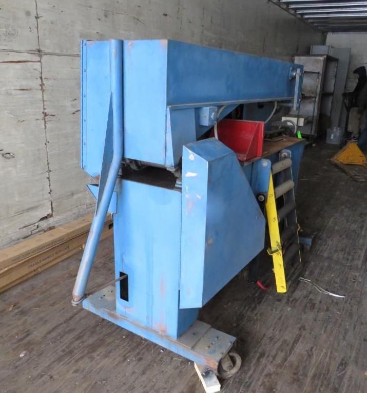 Blue industrial shear machine on wheels inside a warehouse.