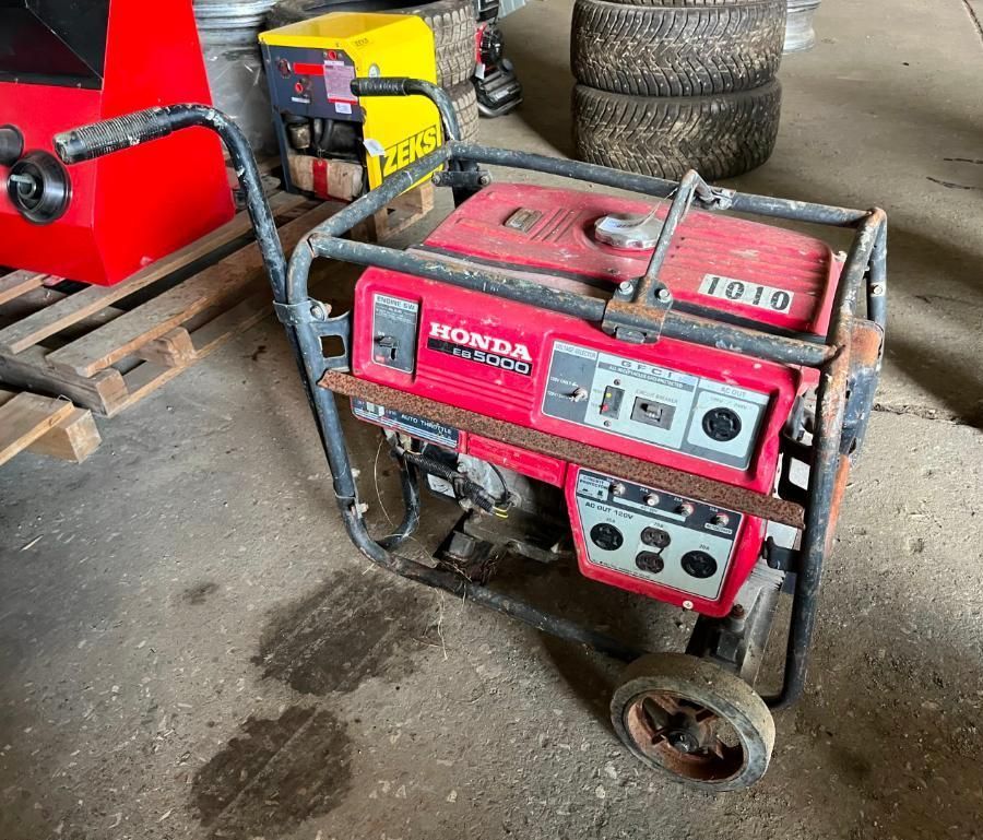 Red Honda generator with black metal frame and wheels on a concrete floor.