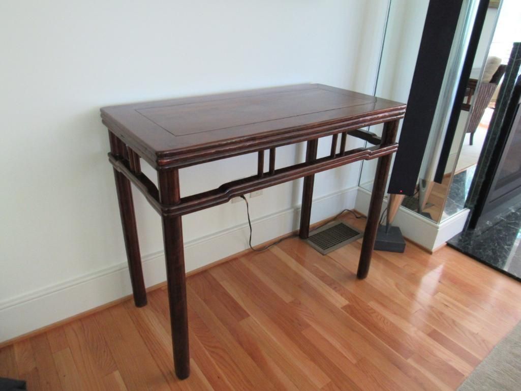 Wooden console table with ornate detailing on a hardwood floor.