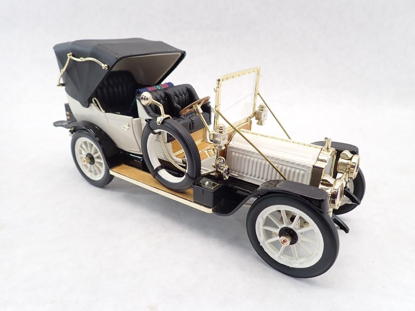Model of an antique car; white body, black top, gold accents.