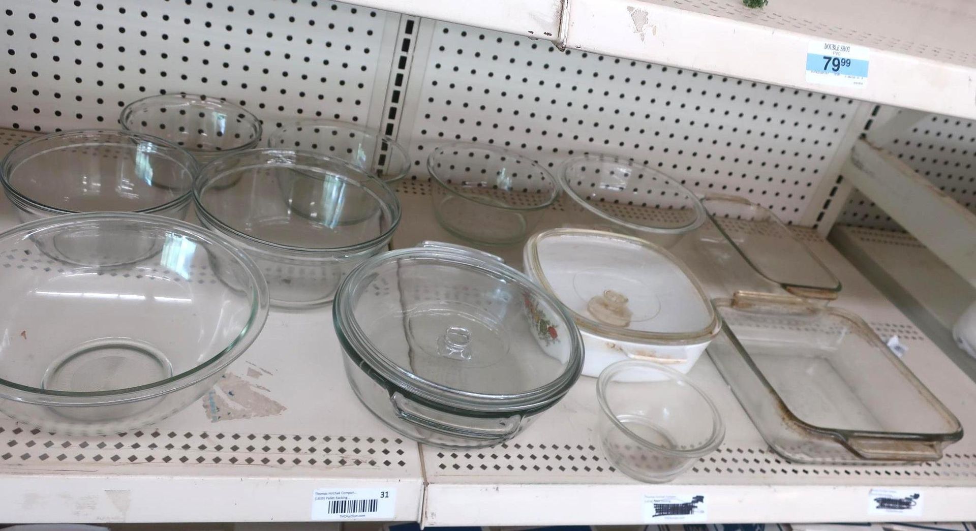 Glass bowls and bakeware on a store shelf, lit by overhead lighting.