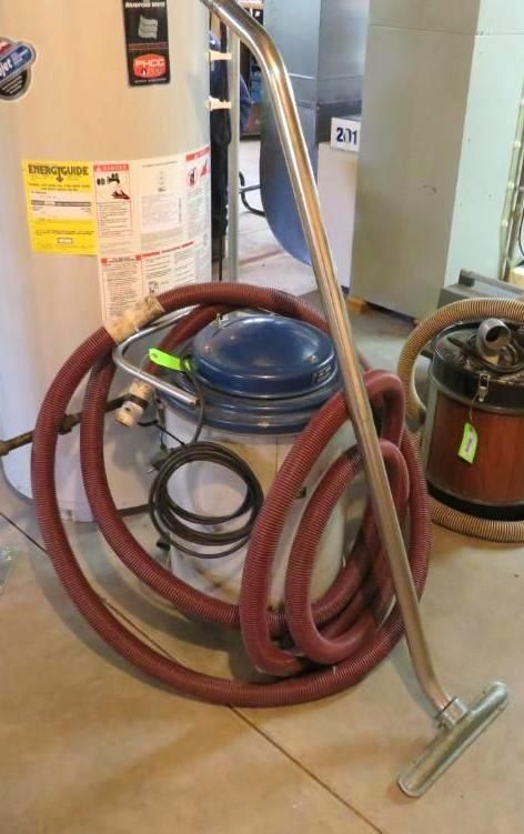 Stainless steel vacuum cleaner with red hose, next to a water heater and other equipment.