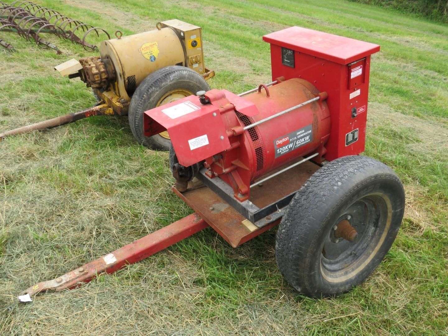 Two red and yellow portable generators on wheels in a grassy field.