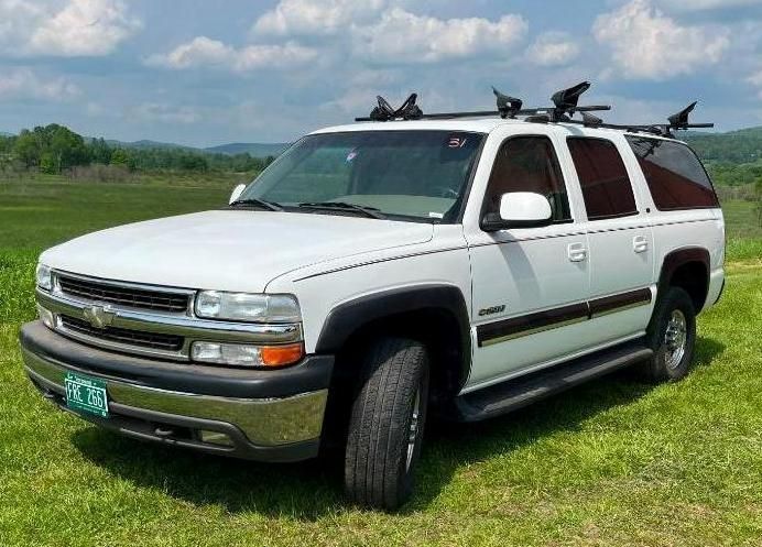 White Chevrolet SUV with roof rack, parked on grass.