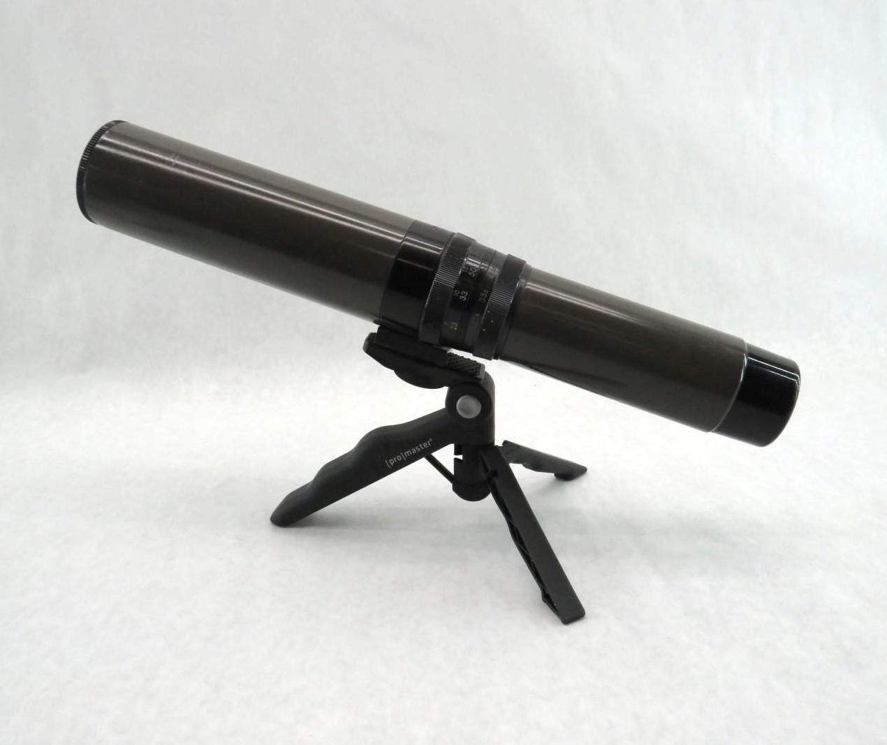 Black spotting scope on a mini tripod, set against a white background.