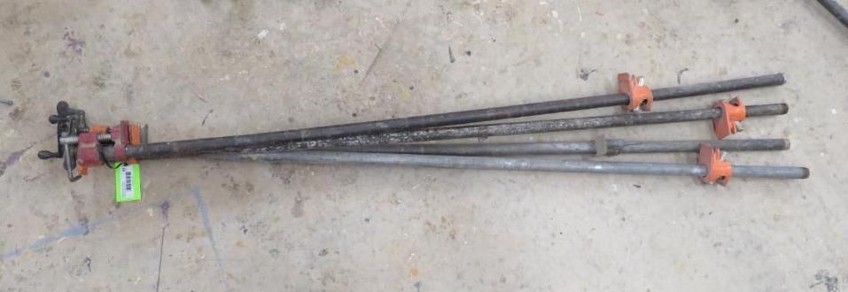 Four metal rods with red connectors resting on a concrete surface.