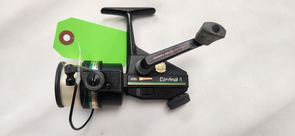 Black and green fishing reel on a white surface with a green price tag.