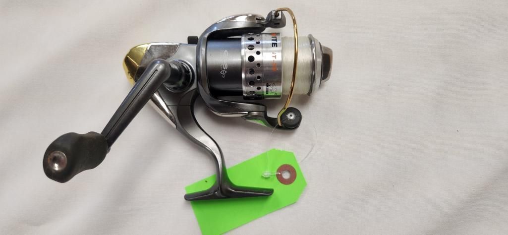 Fishing reel resting on a white surface, with a green tag attached.