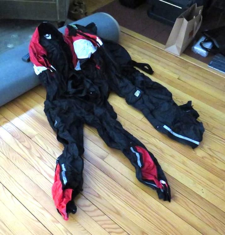 Black and red motorcycle pants and jacket on a wooden floor.