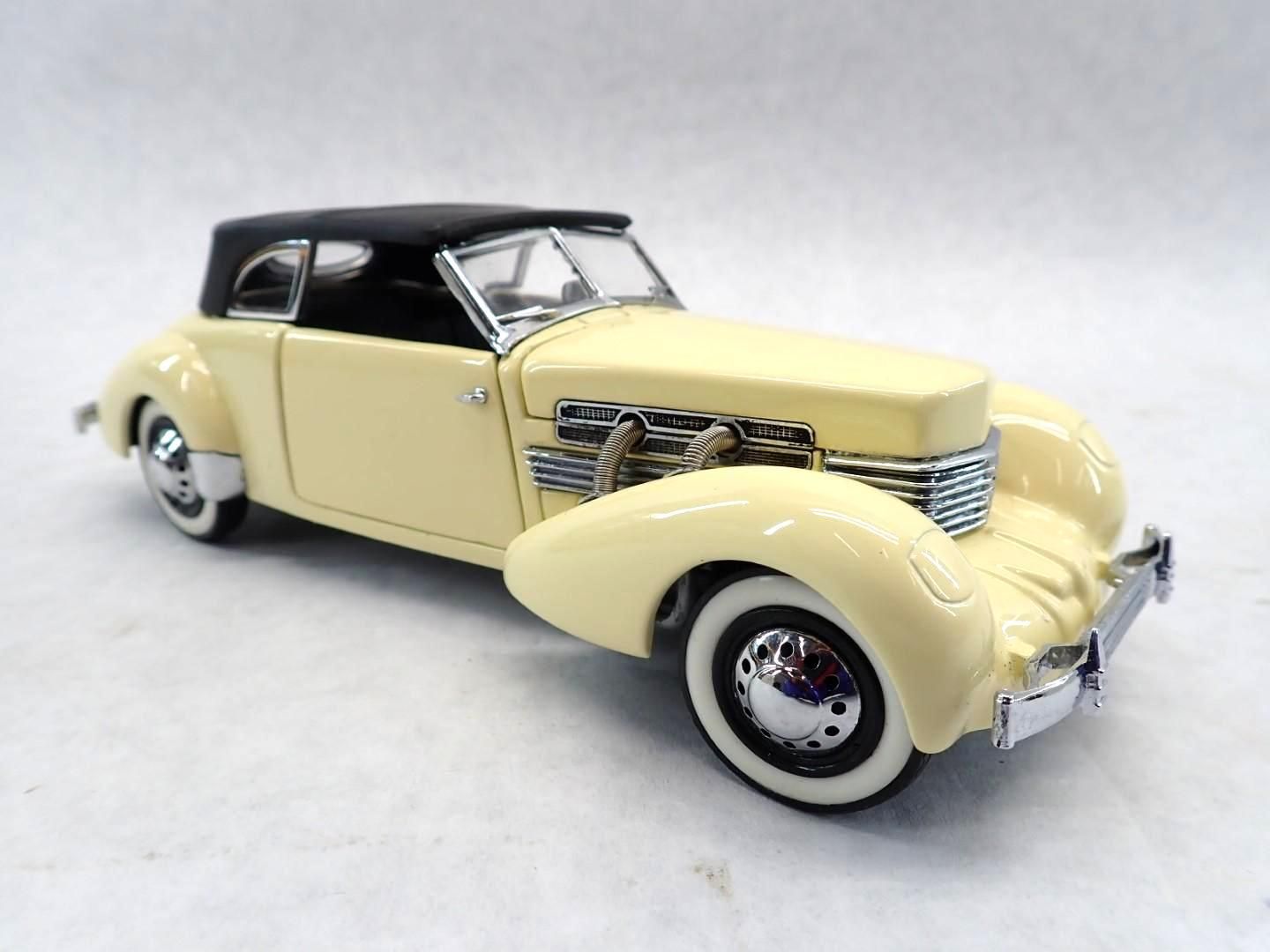 Cream-colored 1937 Cord 812 convertible car model with black roof, chrome details, and white-wall tires.