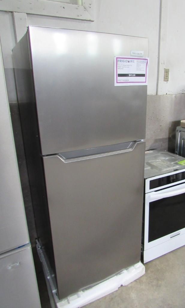 Stainless steel refrigerator in a room, with a white oven and countertop visible.