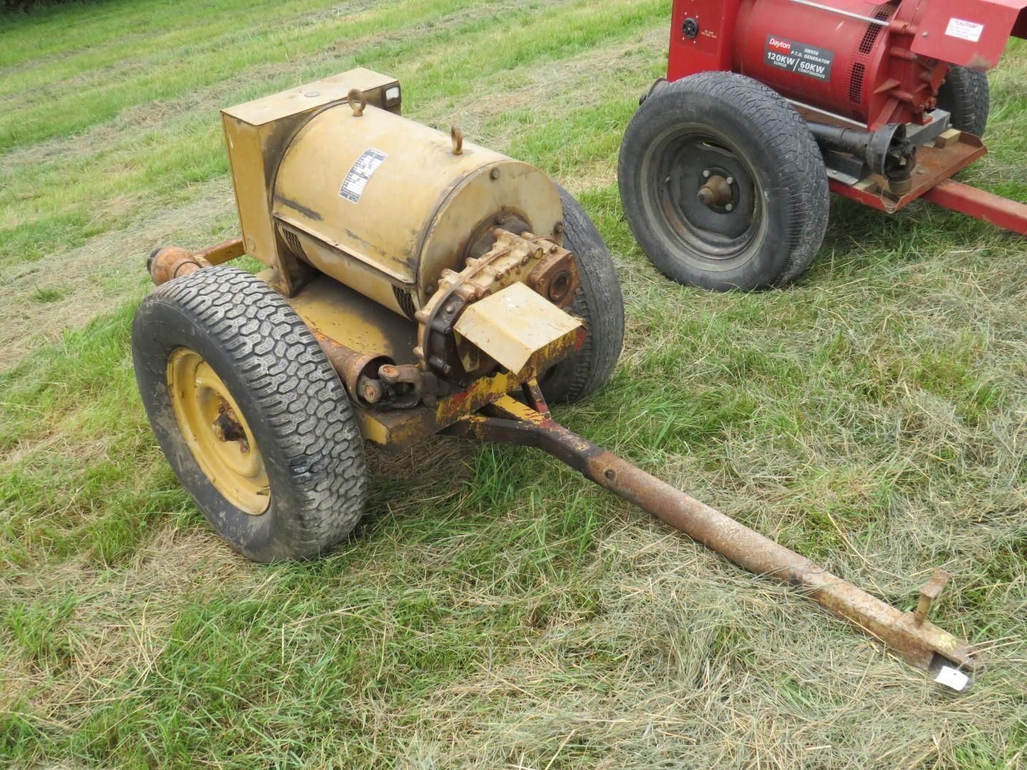 Yellow agricultural blower on wheels, parked on grass.
