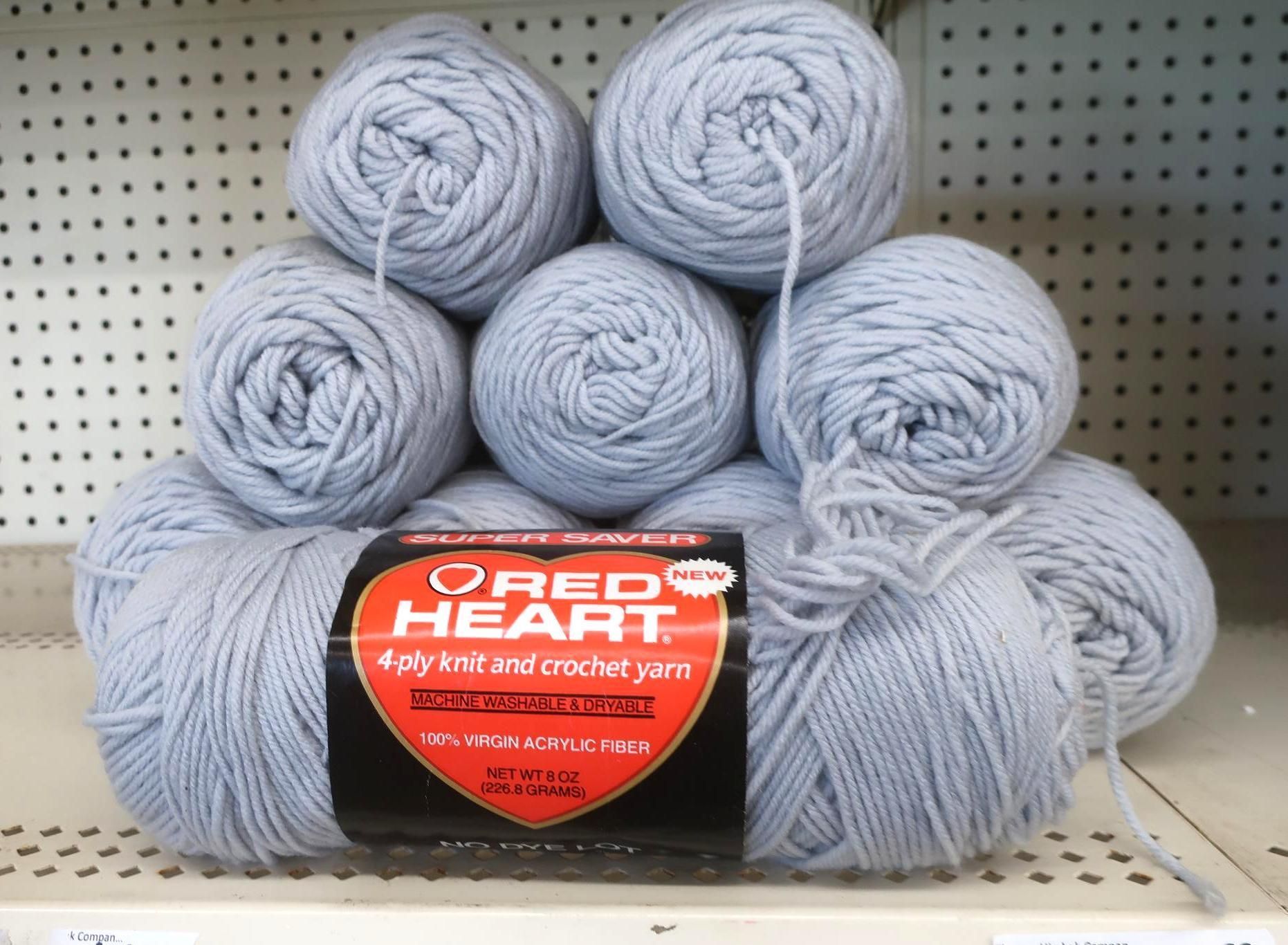 Balls of pale blue Red Heart yarn stacked on a shelf.