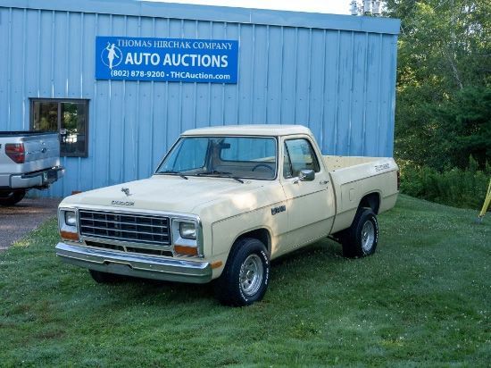 Beige Dodge Ram pickup truck parked in front of a blue auto auction building.