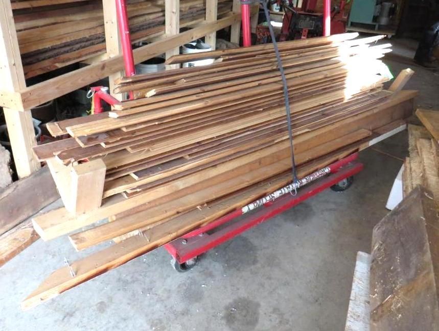 Pile of wooden planks on a red cart inside a workshop.