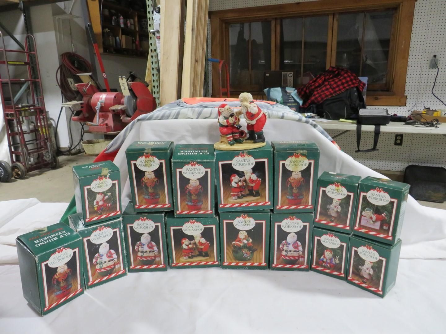 Collection of Christmas figurine boxes and one figurine, arranged on a white cloth.