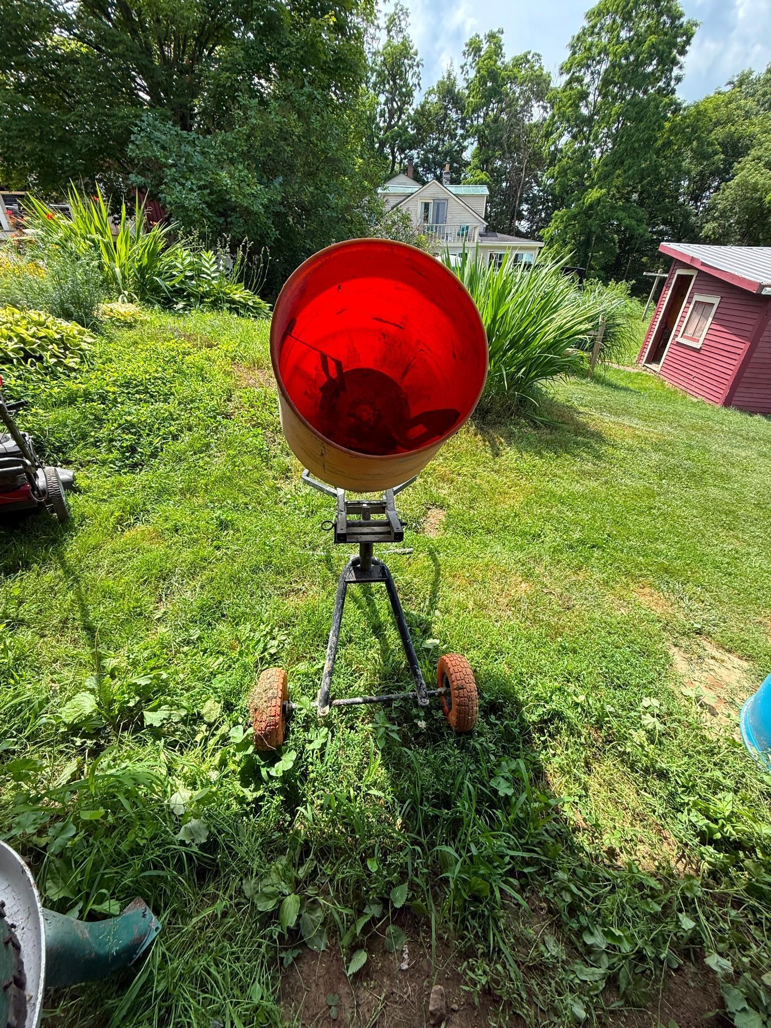Red and yellow contraption on wheels in a grassy yard, sunlight.