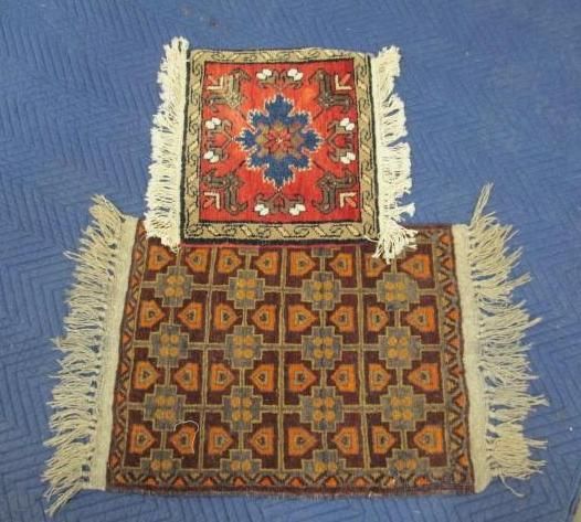 Two small, decorative rugs. The top one is red with a blue floral design, and the bottom is brown with repeating patterns.