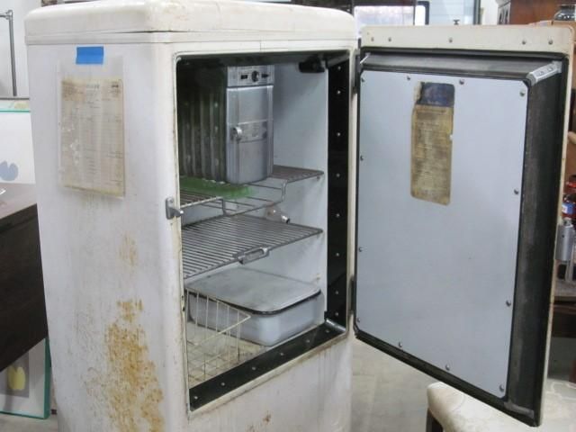 A vintage white refrigerator with the door open, showing shelves and interior components.