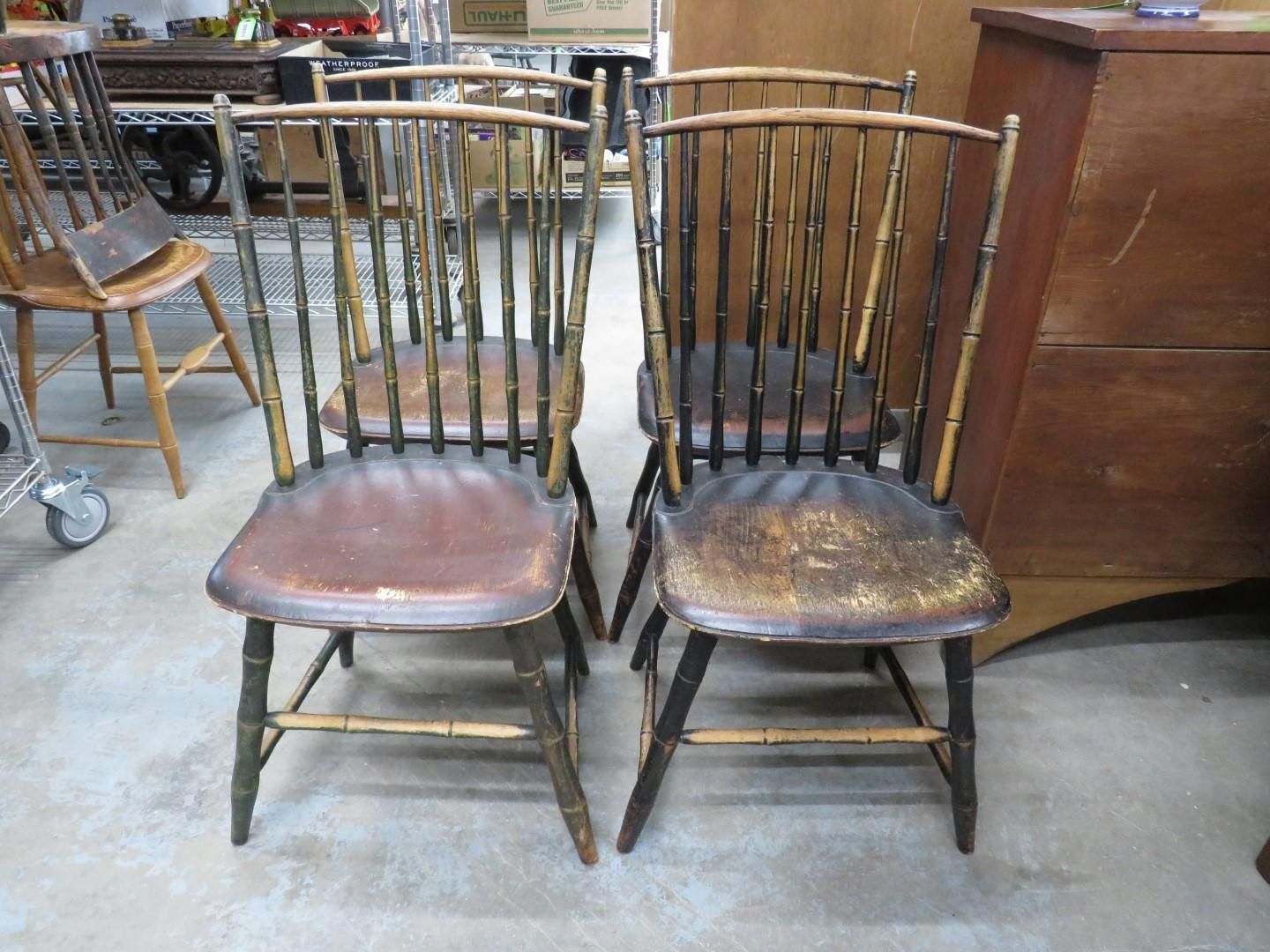 Four antique wooden chairs with spindle backs.