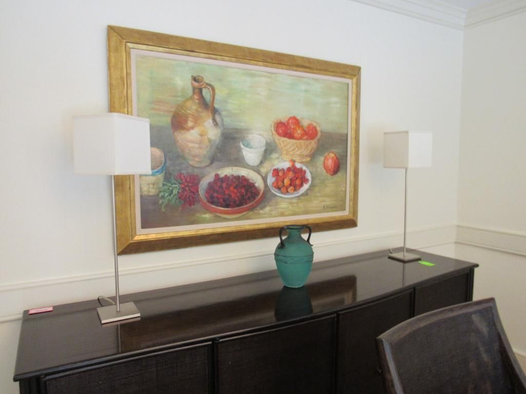 A still life painting hangs above a dark brown sideboard, flanked by two square lamps.
