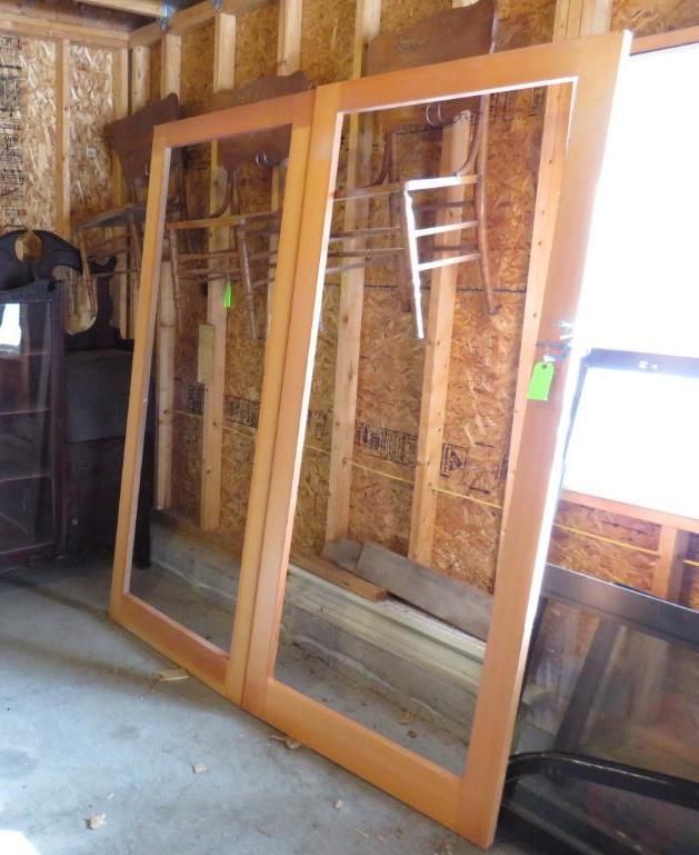 Two wooden framed doors leaning against a wood-paneled wall.