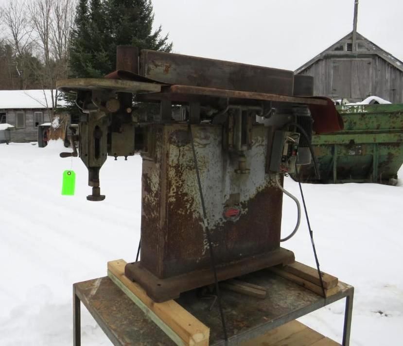 Industrial woodworking planer on a wooden pallet, snowy outdoor setting.