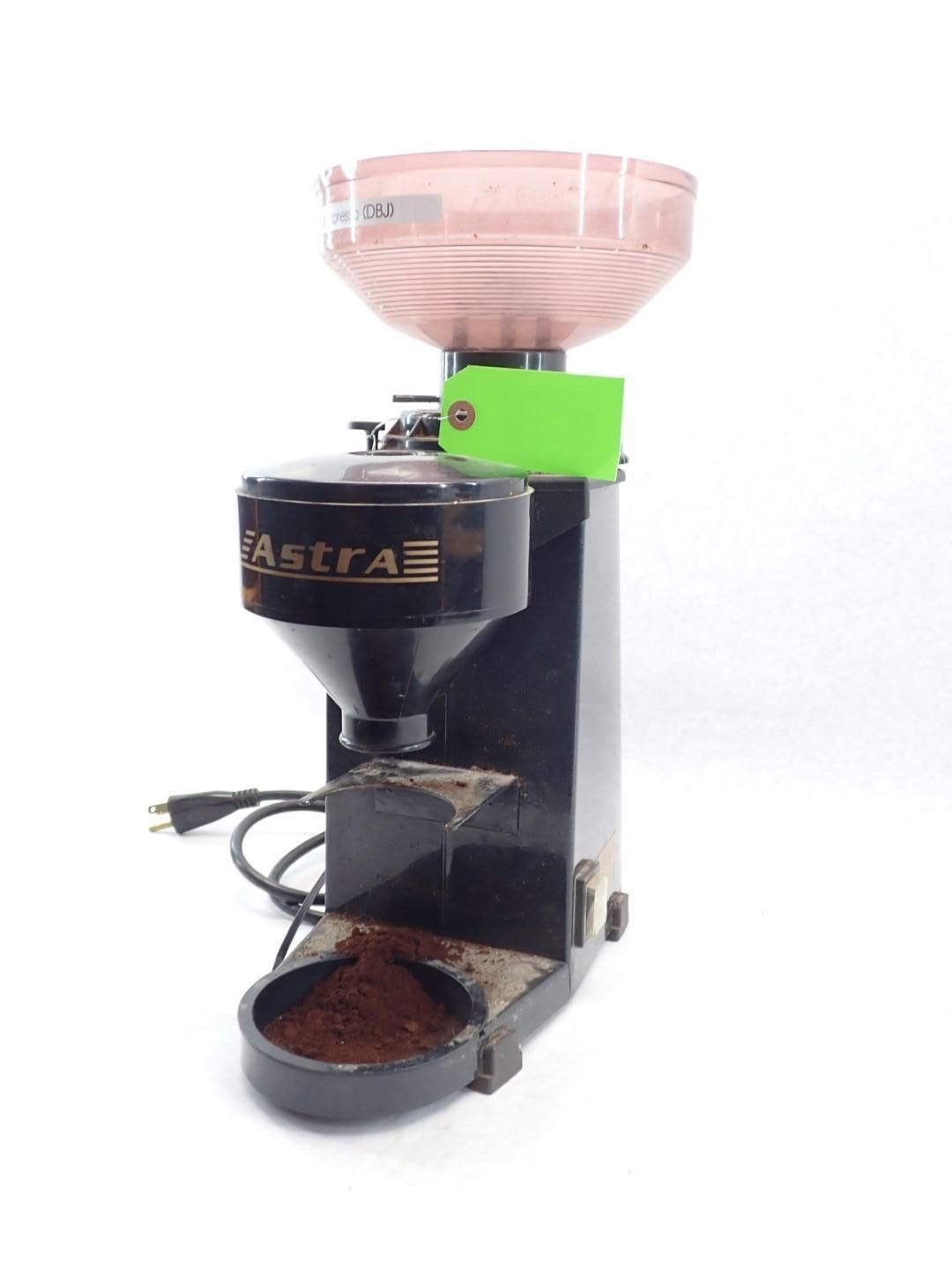 Black Astra coffee grinder with pink hopper, green base, and a bowl of ground coffee.
