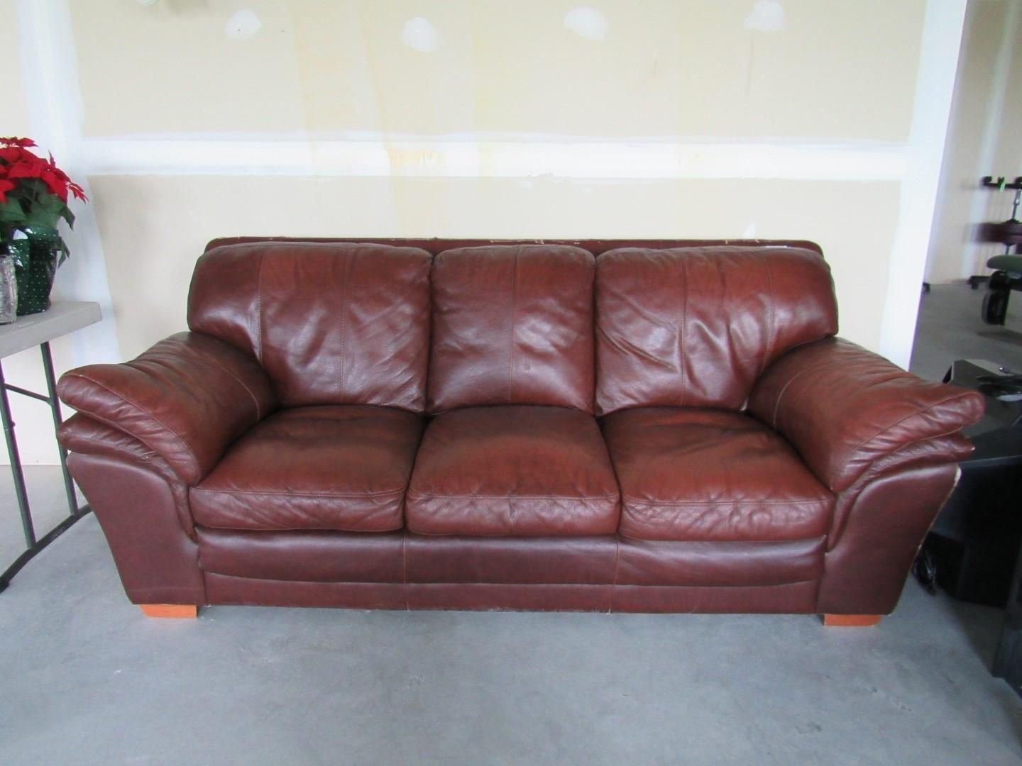 Brown leather sofa in a room with a concrete floor and beige walls.