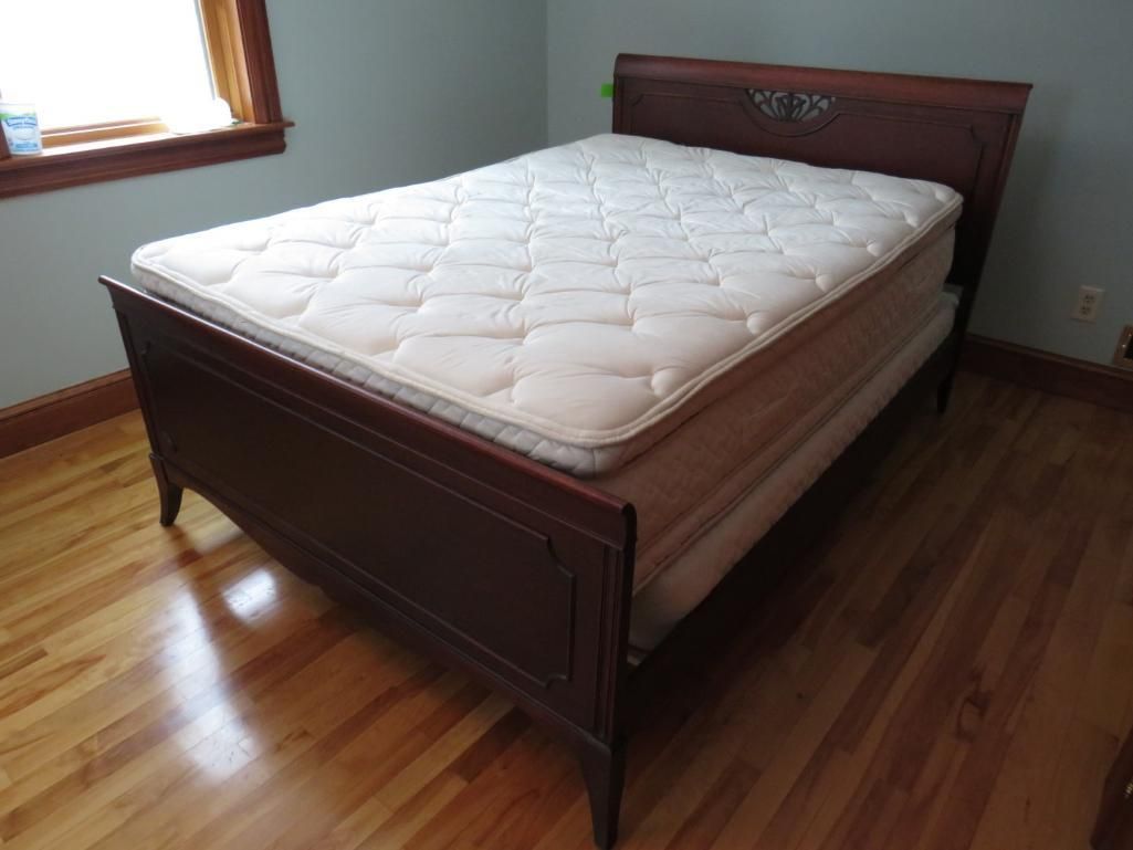 Wooden bed frame with mattress in a room with hardwood floors.