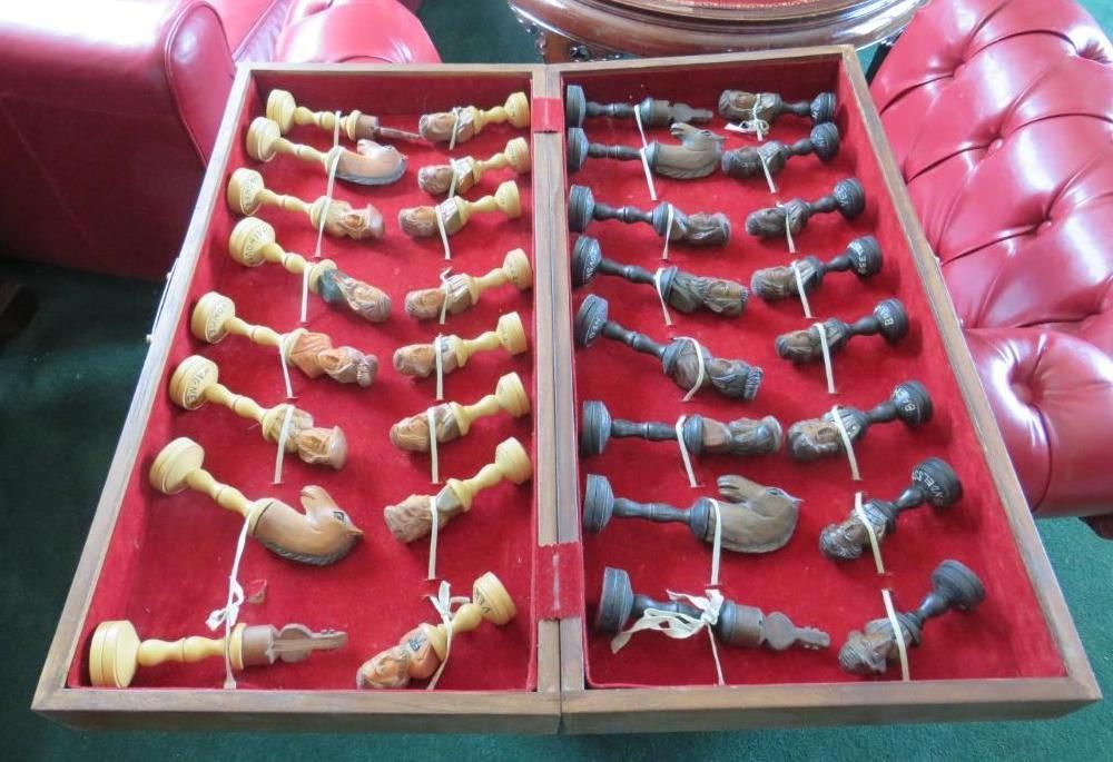 Two wooden trays with carved wooden chess components on a red velvet background.