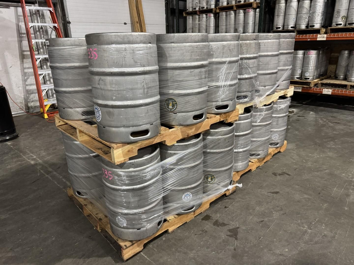 Pallet stacked with beer kegs, inside a warehouse.