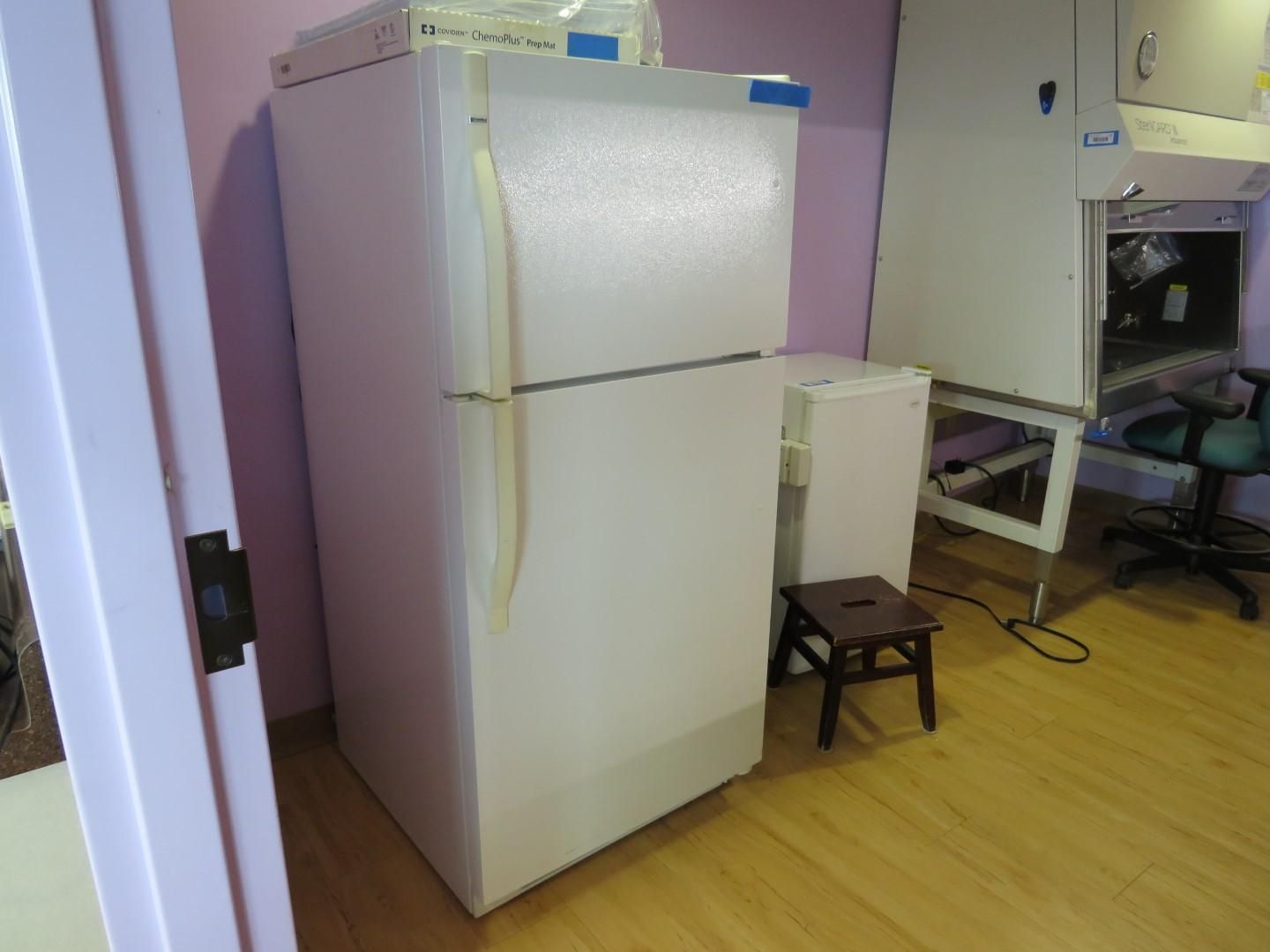 White refrigerator, small stool, cabinet, and lab equipment in a room with wood floors and purple walls.