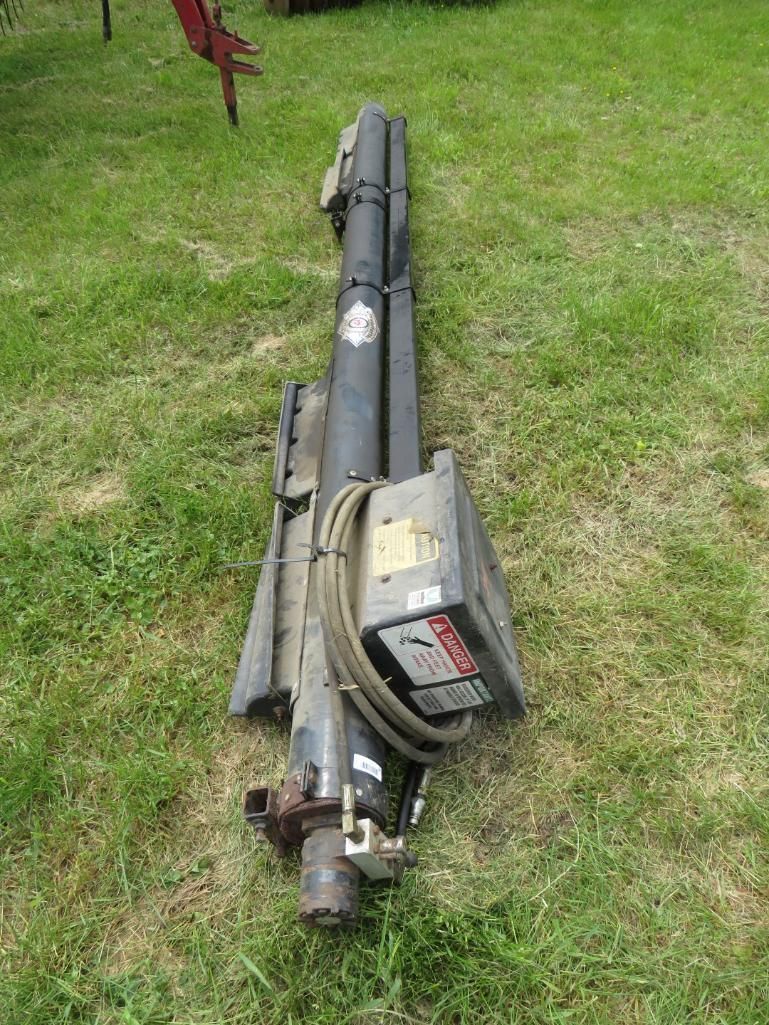 Folded black agricultural machinery lying on green grass.