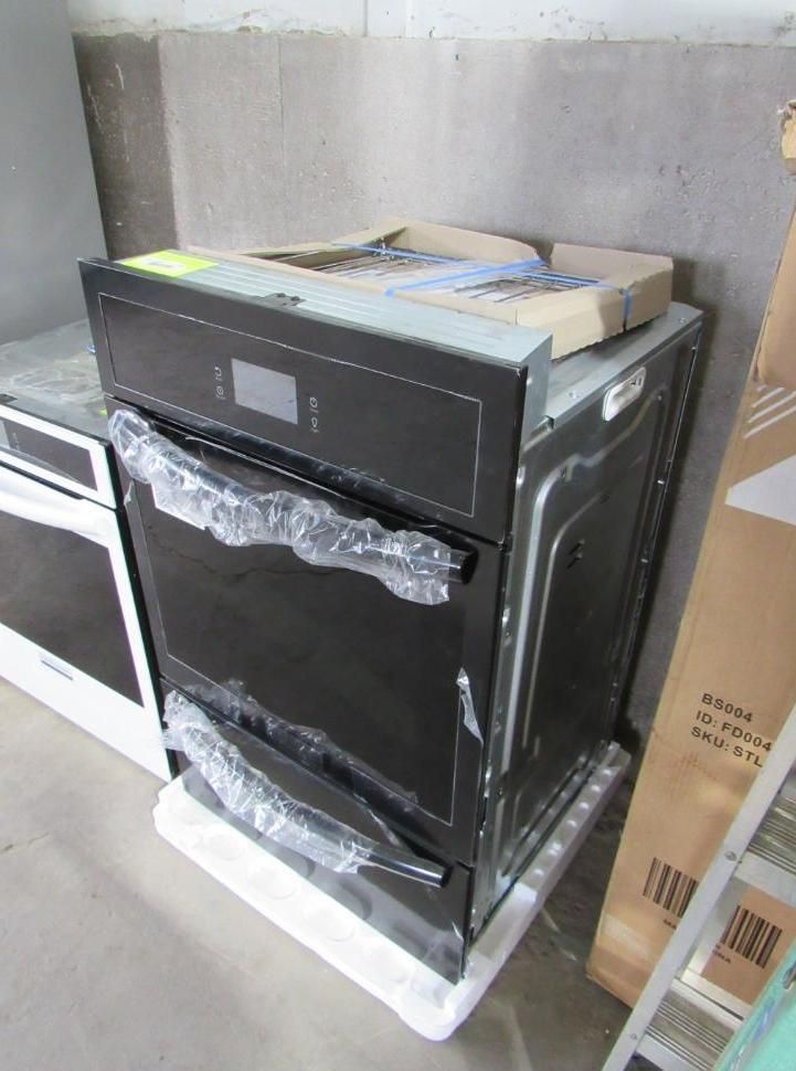 Black oven in packaging, digital display, sitting on white foam, in storage area.