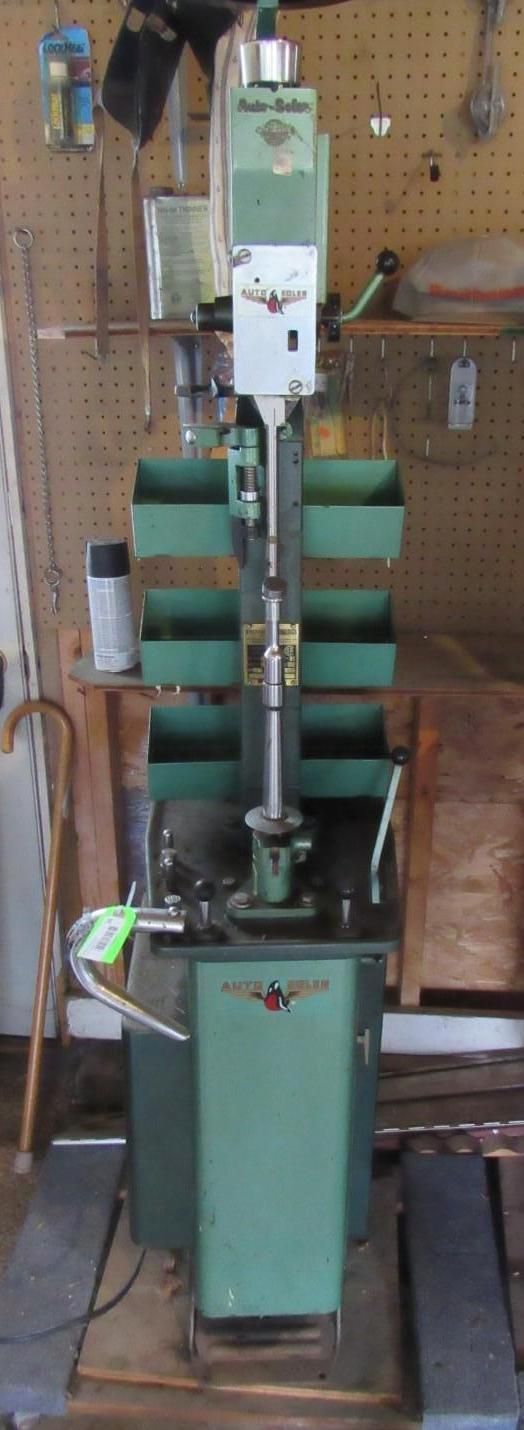 A tall, green milling machine in a workshop setting. It has multiple trays and a control panel.