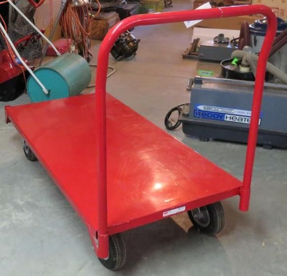 Red platform cart with a U-shaped handle, four wheels, on a concrete floor.