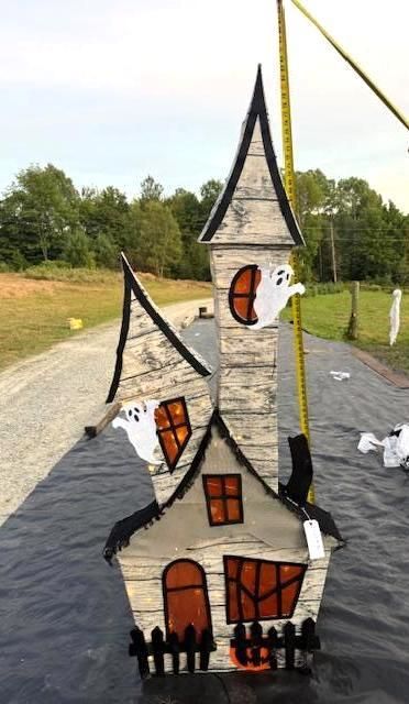 Wooden Halloween haunted house decoration with ghosts, on black tarp. Halloween Decoration.