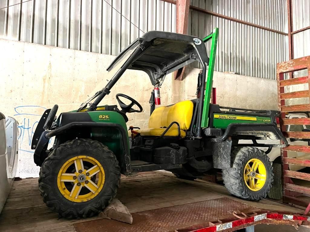 Green and yellow John Deere Gator utility vehicle parked inside a building.
