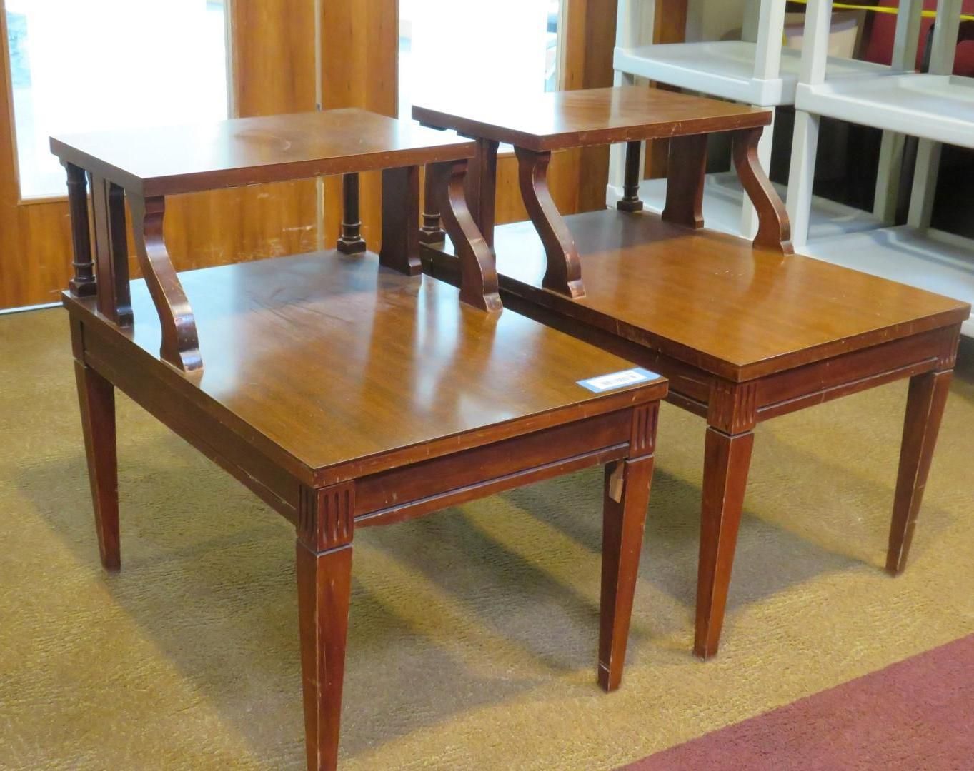 Two wooden side tables with two-tiered surfaces and curved supports, in a brightly lit room.