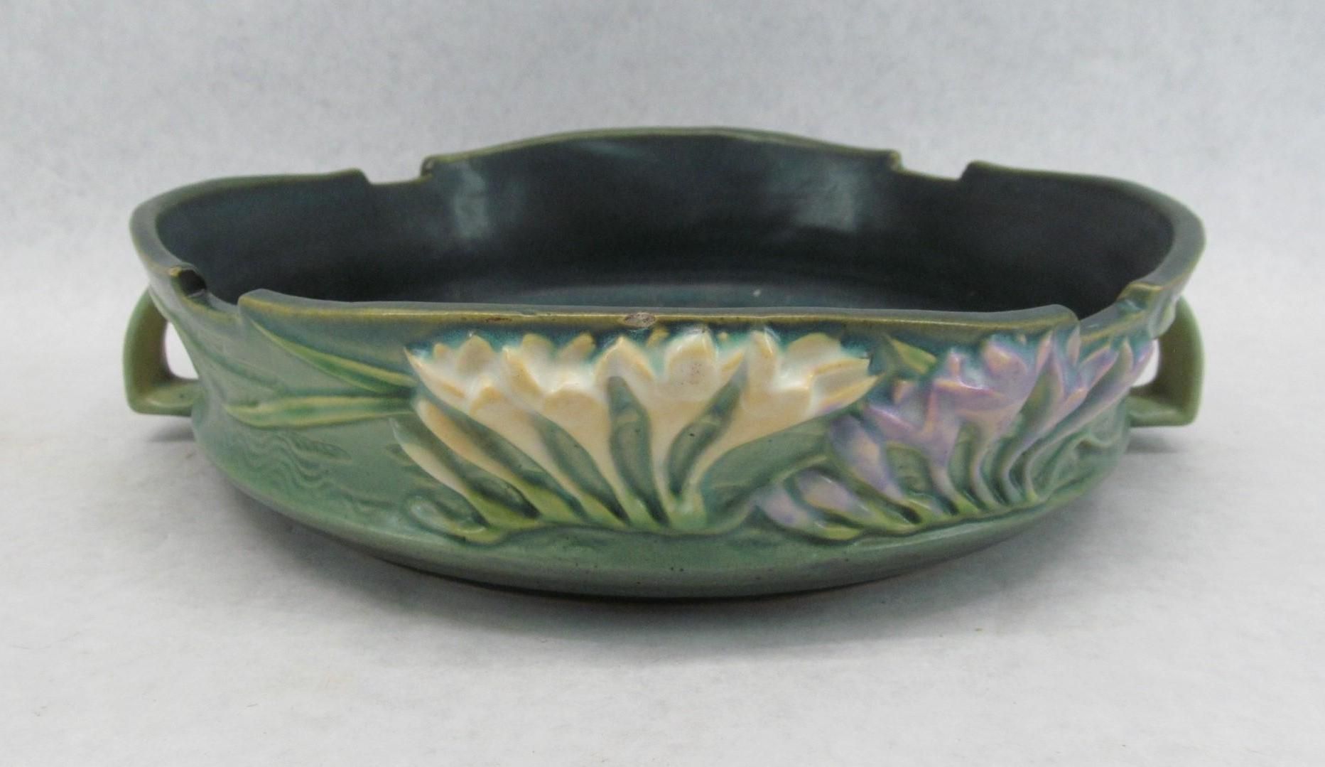 Green ceramic bowl with embossed flowers, handles, and dark interior.