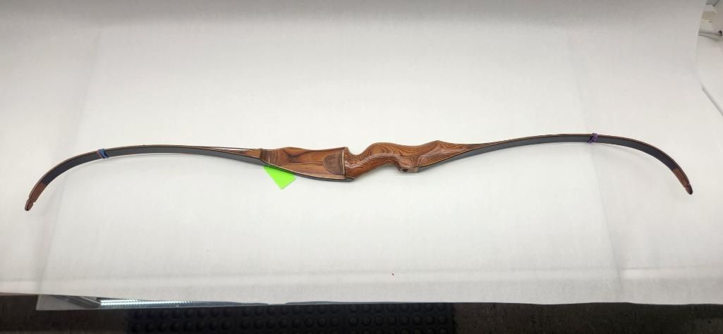 A wooden recurve bow, horizontally centered, set against a white surface.