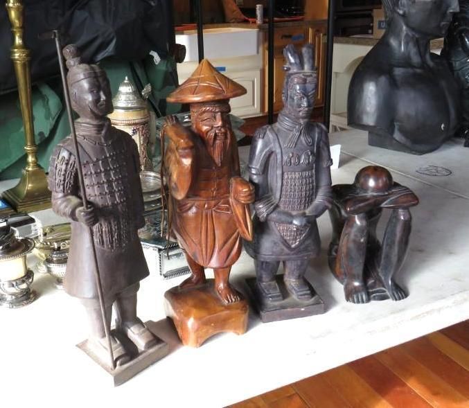 Four wood carvings: a soldier, an Asian figure, a warrior, and a kneeling person with a hat.