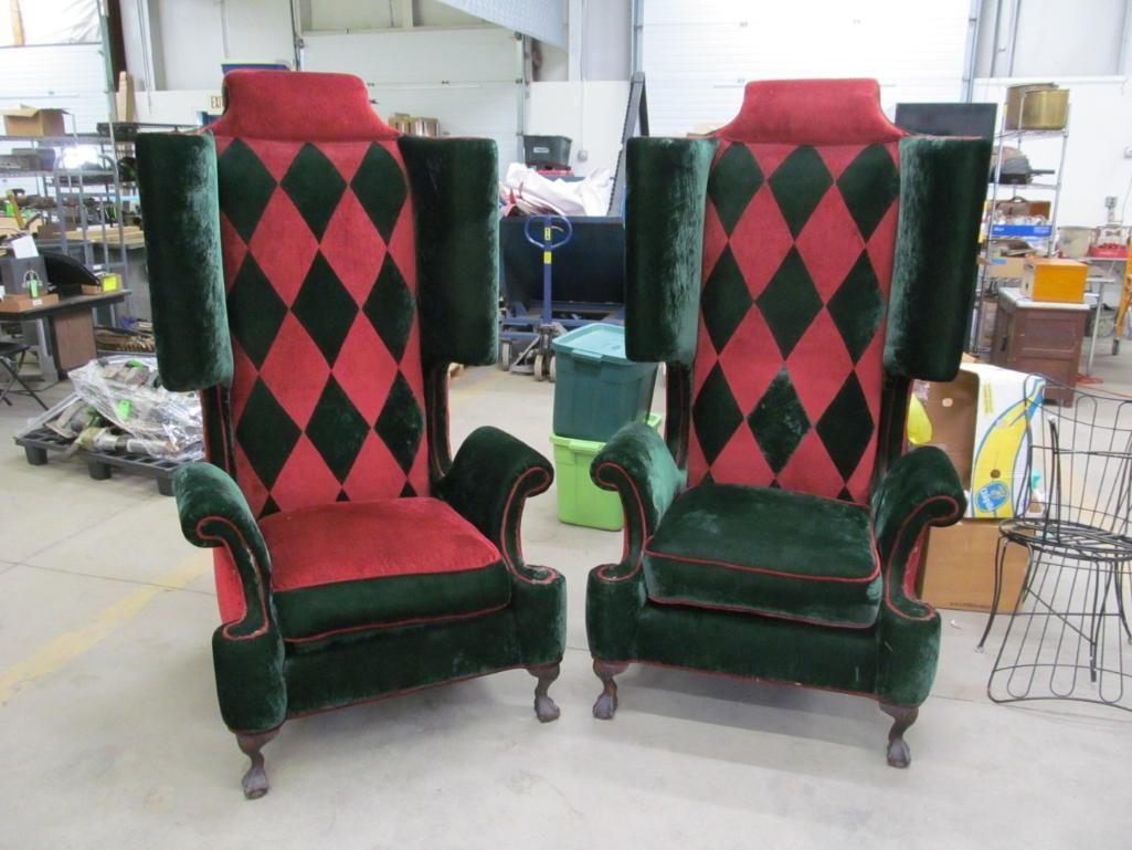 Two ornate green and red velvet armchairs, with tall backs in a warehouse.