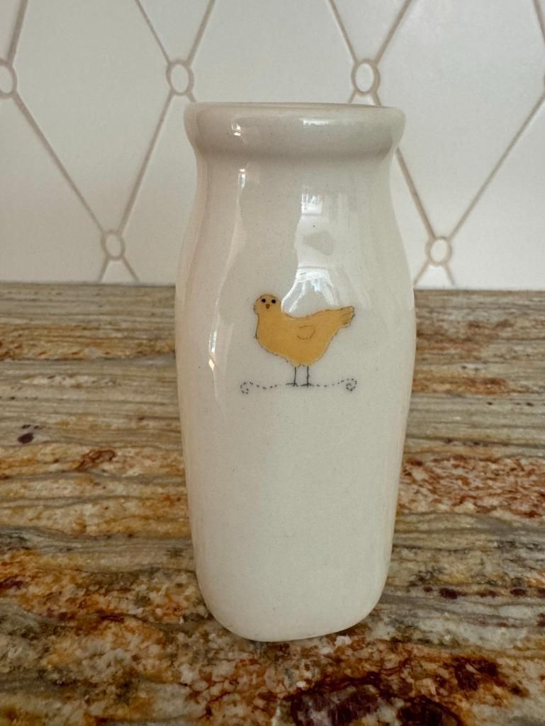 White ceramic vase with a yellow chicken illustration.
